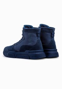 Baskets mi-hautes bleu marine avec un dessus en daim, une semelle en caoutchouc durable et un accent de logo proéminent sur le côté.