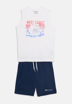 Haut sans manches blanc avec imprimé rouge et bleu "West Coast Music" et palmier, associé à un short bleu marine à cordon avec logo Champion.
