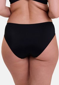 Bas de bikini noir, couvrant entièrement, fabriqué en tissu lisse ; présente un design sans couture sans quincaillerie ni motifs visibles.
