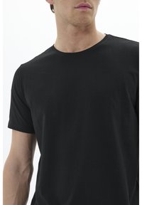 Melnas īsās piedurknes T-krekls no gludas kokvilnas auduma. Raksturīga apaļa kakla izgriezne un brīvs piegriezums. Vienkāršs dizains, bez rakstiem vai akcentiem.