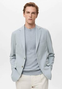 Light blue blazer made of a soft fabric, featuring notched lapels, a single-button closure, and a chest pocket, layered over a matching knit sweater.