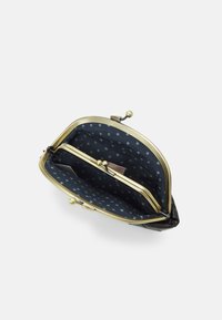 Black leather purse with a bronze frame, featuring a navy interior lined with white star patterns and two compartments for organization.