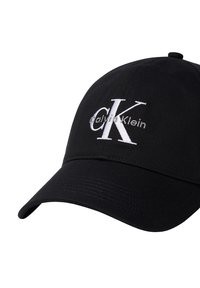 Schwarze Kappe aus Stoff mit gebogenem Visier. Auf der Vorderseite befindet sich ein weiß gesticktes "CK" und "Calvin Klein" in moderner Schrift.
