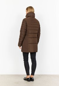 Brun puffjacka med hög krage och vertikal sömnad, som har en figursydd design och en jämn, glansig yta.