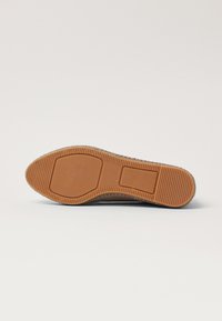 Shoe sole with a textured brown rubber material, featuring a patterned grip and a rectangular accent through the center.