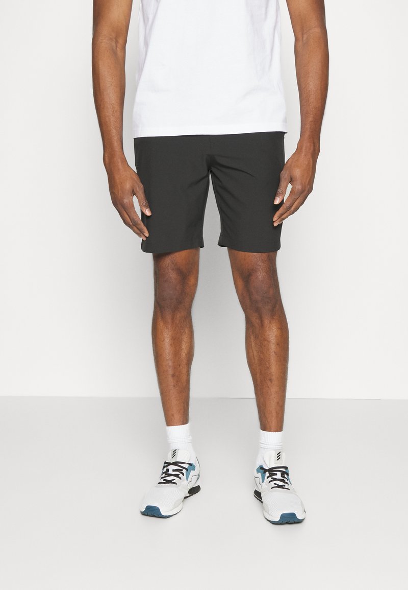 Sorte shorts laget av lett materiale, med et enkelt design og en over-kneet snitt. Brukt med en hvit t-skjorte og sneakers.