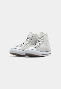 Høysåle sneakers i lys grå skinn, med hvit gummitåhette, snøring og side-logos, samt en teksturert brun gummisåle.