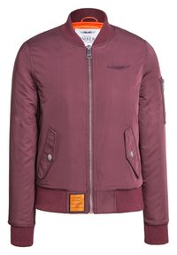 Giacca bomber bordeaux con zip frontale, polsini a costine, due tasche anteriori e una tasca con zip sulla manica. Presenta un rivestimento arancione e un'etichetta.