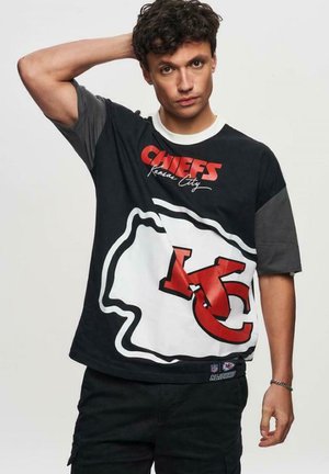 Sort og grå kortærmet t-shirt med teksten "Chiefs Kansas City" og et markant rødt KC-logo med en hvid kant.