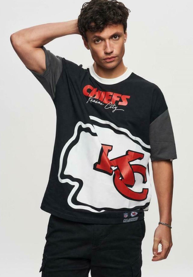 Sort og grå kortærmet t-shirt med teksten "Chiefs Kansas City" og et markant rødt KC-logo med en hvid kant.