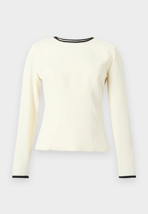 Krémový top s dlouhým rukávem, přiléhavým střihem, zvýrazněnými švy a černým výstřihem a manžetami na rukávech. Hladká textura a strukturovaný tvar.