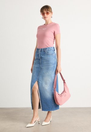 T-shirt ajusté rose clair, jupe en denim taille haute avec une fente sur le devant, chaussures à talons blanches et sac à épaule rose. Textures lisses, design décontracté.