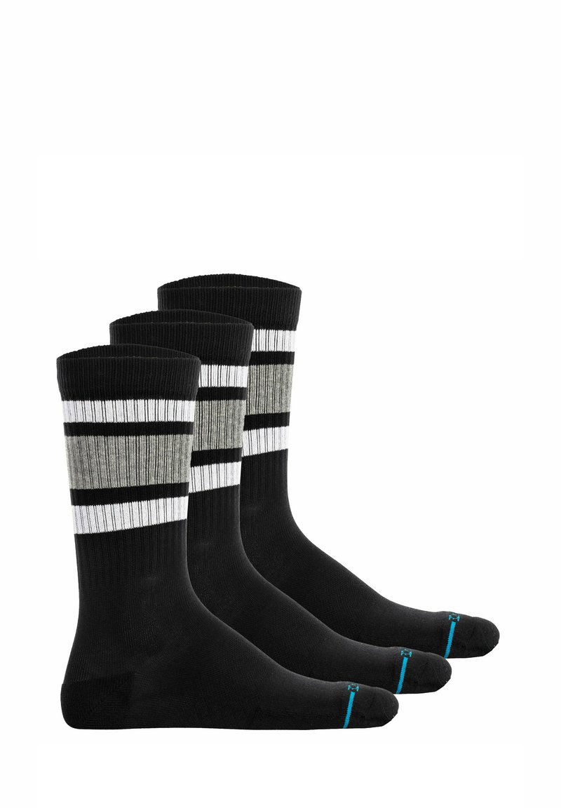 Calcetines negros con una textura acanalada, que presentan dos rayas blancas y una gris en la parte superior y un acento azul en la puntera. Se muestran tres pares.