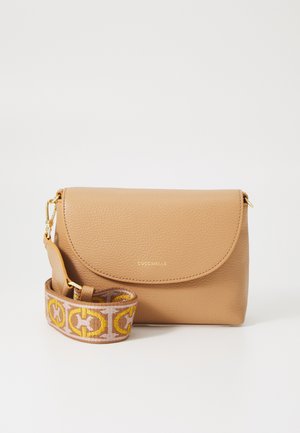 Beige leren schoudertas met een ronde flap, voorzien van een gouden logo en een patroonriem in roze, beige en gele accenten.