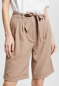 Shorts de talle alto en color beige con un cintúrón atado, pinzas y dobladillos enrollados. Elaborados con una tela suave que proporciona un aspecto entallado.