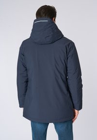 Giacca impermeabile di un blu scuro con cappuccio, dotata di una texture liscia e una striscia bianca a contrasto sul retro, progettata per attività all'aperto.