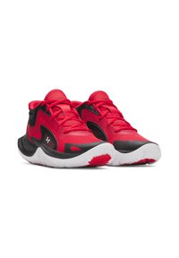 Chaussures de sport rouges avec des accents noirs, tige en maille, semelle rembourrée et semelle extérieure en caoutchouc texturé avec un motif en vagues.