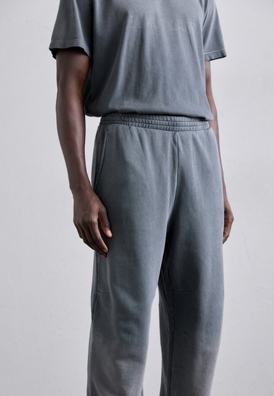 Tricou din bumbac gri cu amestec și pantaloni de trening asortați, cu un tiv elastic, croi lejer și o textură subtilă cu un finisaj estompat.