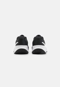 Black athletic shoes with textured fabric upper, white accents, and a contrasting rubber sole featuring a zigzag pattern.