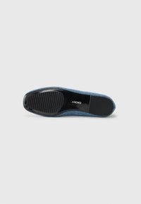 Blue slip-on shoe with a textured fabric upper and a black rubber sole featuring ribbed grip detailing. Logo embossed on the sole's surface.