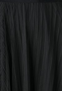 Černá skládací tkanina s texturovaným povrchem. Vertikální pruhy vytvářejí plynulý design, který zdůrazňuje pohyb a vizuální zajímavost. Hladký pas.