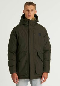 Chaqueta de plumas verde con un cuello alto y capucha, que cuenta con un zipper frontal, dos grandes bolsillos laterales y un pequeño bolsillo en la manga.