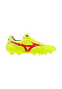 Botas de fútbol amarillas brillantes con acentos rojos, hechas de material sintético suave. Presentan una punta redondeada y clavos de plástico moldeados.