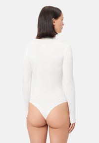 Body de manga larga en blanco, con cuello alto y diseño ajustado, con parte trasera tipo tanga y tela lisa y elástica.