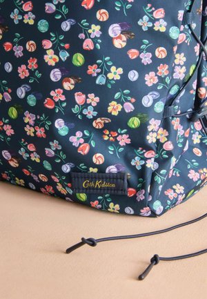 Námořnický květinový batoh s barevnými vzory květin a lastur, s hladkým povrchem a zlatou štítkem s logem značky Cath Kidston.