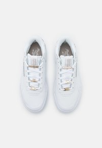 Paire de baskets blanches Reebok Classic avec des accents dorés sur les lacets, vues de dessus sur un fond blanc.
