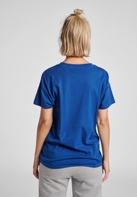 Blå bomullströja med rundad hals, korta ärmar och en lös passform. Slät textur, minimalistisk design utan grafik eller accenter.