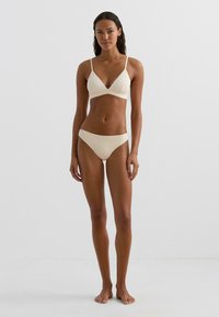 Kremowy zestaw bikini z fakturowanej tkaniny; trójkątny top i niskie figi; regulowane ramiączka; dopasowany krój; minimalne krycie.