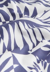 Fehér anyag tengerészkék zebra csíkos mintával, lágy redőkkel és sima textúrával közelről bemutatva.