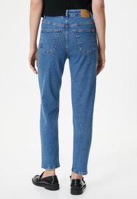 Ljusblå denimjeans med rak ben-design, som har två bakfickor, en läderpatch vid midjan och subtila blekningsdetaljer.