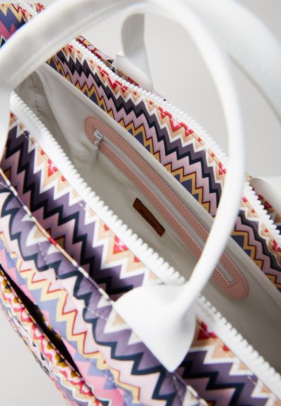 Geantă tote deschisă cu un model zigzag multicolor, mânere albe și interior bej, având un mic buzunar cu fermoar și eticheta de brand din piele.