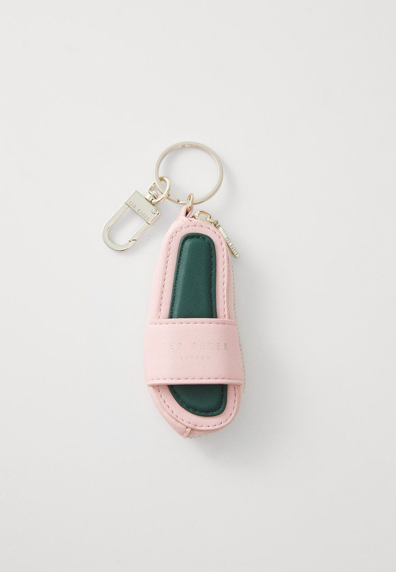 Nøkkelring formet som en rosa sklisandal med grønt interiør. Har gullfarget maskinvare og preget logo. Glatt tekstur, kompakt design.