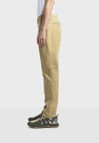 Khaki-Chinos mit geradem Schnitt, aus einem Baumwollmischgewebe gefertigt. Sie verfügen über seitliche Taschen, Gesäßtaschen und ein dezentes Taillendetail.