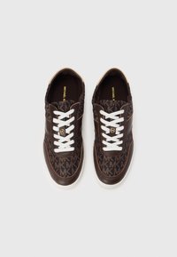 Brune sneakers med et MK-logo mønster, hvide snørebånd, læderdetaljer og en gummisål. Fladt design med rundet tå.