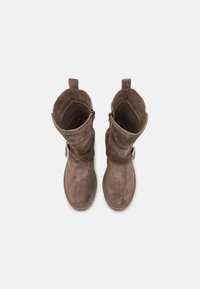Botas de ante marrón con una altura hasta la mitad de la pantorrilla, acento de hebilla en el lateral y un acabado texturizado. Presentan una punta redondeada y suela de goma.