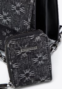 Schwarze und graue Textiltasche mit passendem Reißverschluss-Geldbeutel, der ein Schneeflockenmuster und Metallbeschläge aufweist.