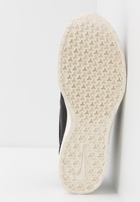 Mustan ja valkoisen Nike-tennaritossun pohja, jossa on tekstuurinen kuusikulmainen urakuvio ja Nike-swoosh-logo pohjassa.