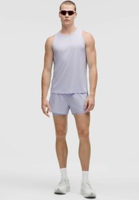 Top e pantaloni sportivi di colore viola chiaro, realizzati in un tessuto morbido. Indossati con scarpe bianche e occhiali da sole. Design semplice, senza motivi.