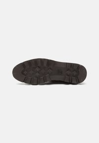 Black rubber sneaker sole with prominent tread pattern and lateral grooves. Features logo imprint in the center. Textured for grip.