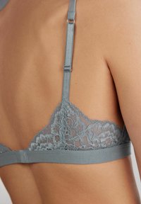 Lichtgrijze bralette met kantcups met bloemenpatroon, verstelbare bandjes en een zachte stoffen band onder de buste.
