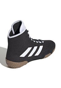 Svart nät högsko med vit tre-stripesdesign, texturerad yta och gummisula med mönstrat grepp för bra fäste.