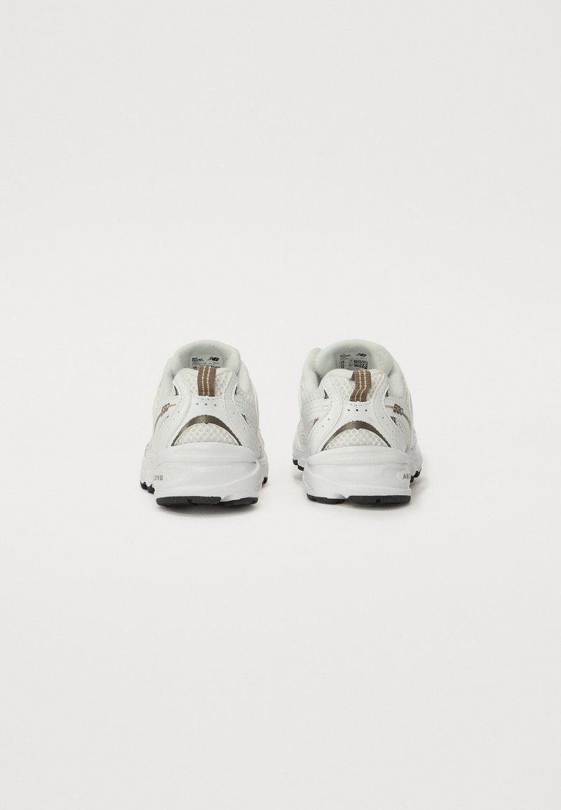 Witte sportschoenen met gaasdetails, textuurelementen en een zwarte rubberen zool. Voorzien van een achterste trekband en vetersluiting.