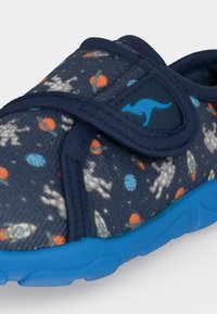 Chaussure enfant bleu marine avec motif à thème spatial, semelle bleue et logo kangourou sur la bride Velcro réglable.