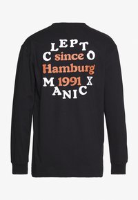 Schwarzes Langarm-T-Shirt mit auffälligem, mehrfarbigem Text auf der Rückseite: "CLEPTOMANIC seit Hamburg 1991", in unterschiedlichen Schriftarten.