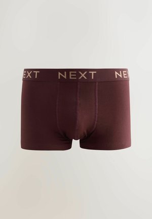 Pantaloni scurți boxer cărămizii, realizați dintr-un material moale, cu o bandă largă inscripționată cu „NEXT” în auriu. Au o croială strânsă și fără modele vizibile.