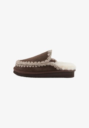 Brune ruskinds slippers med en blød hvid pelsforing, der har en flettet kant langs åbningen og en flad gummisål.
